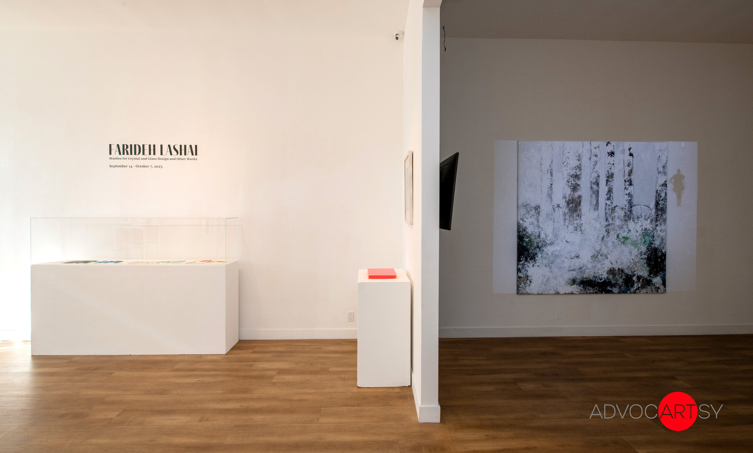 Two walls in ADVOCARTSY's West Hollywood gallery space; one reads "Farideh Lashai: Studies for Crystal and Glass Design and other works," and the other wall shows a large painting with an overlaying projected video.
